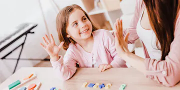 Little girl holding 5 fingers up to practice math