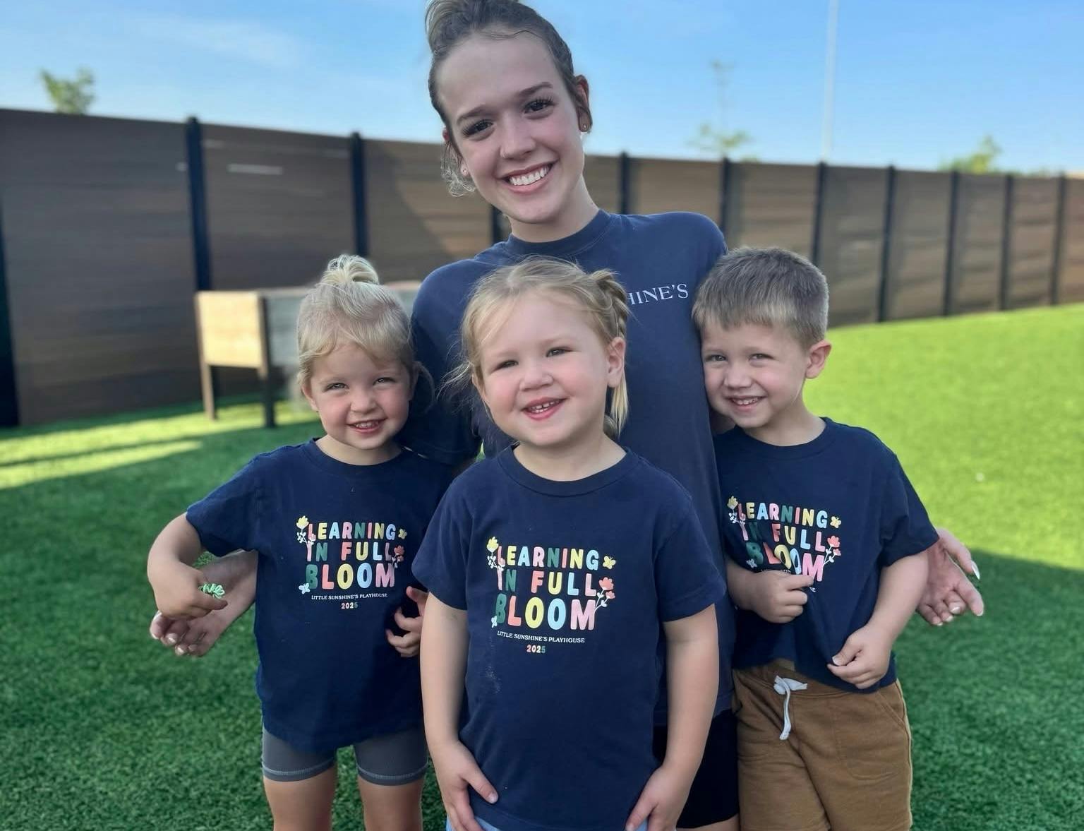 A Little Sunshine's Playhouse teacher poses with three of her adorable students.
