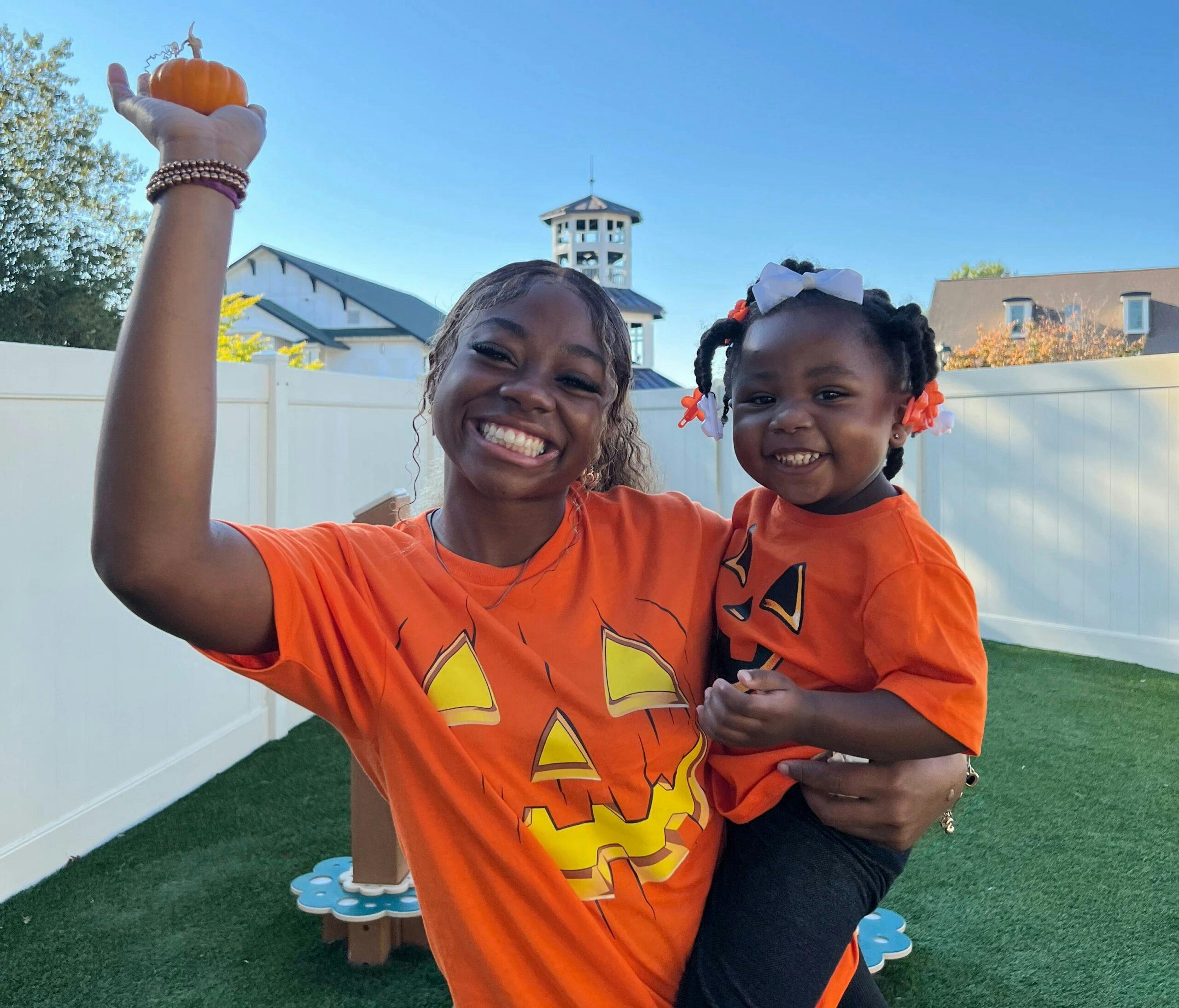 One of our teachers at Little Sunshine's Playhouse of Roswell is holding a pumpkin with one of her adorable students!